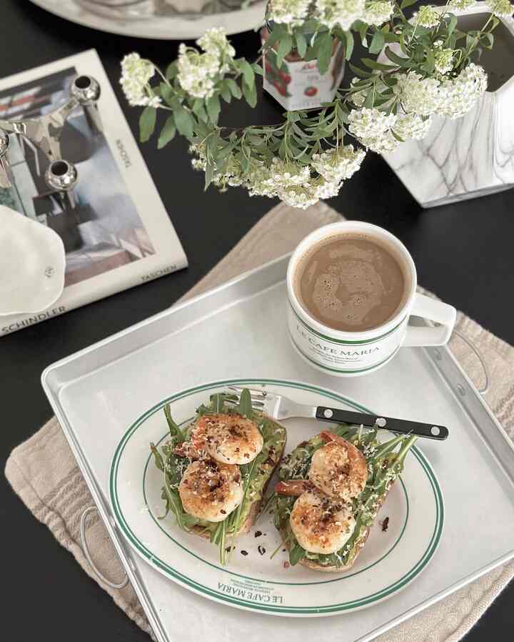 White and green-toned home cafe setup featuring a stainless steel tray with a mug and open toast, creating a stylish cafe ambiance