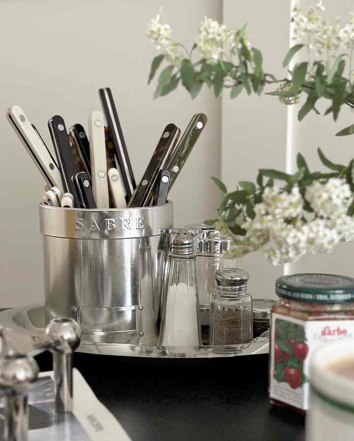 ステンレスとシルバートーンのダイニング、中央にカトラリーと調味料が置かれたメタルトレイが配置された清潔感のあるインテリア