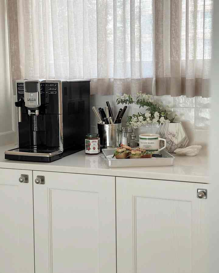 ホワイトとベージュ調のキッチン、調理器具とガジアアニマコーヒーマシンが配置された清潔感のあるおうちカフェ空間