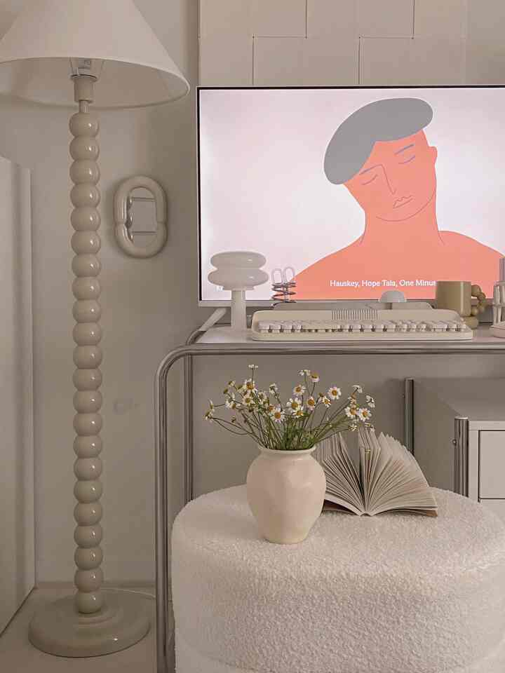 白とベージュのトーンのワンルームリビング、モダンなテレビ台とフロアランプが配置されたシンプルな空間