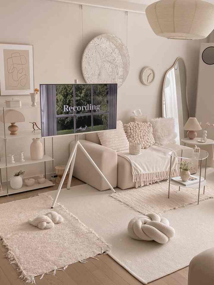 Beige and white toned living room featuring a sofa and tripod TV stand in a natural modern setting
