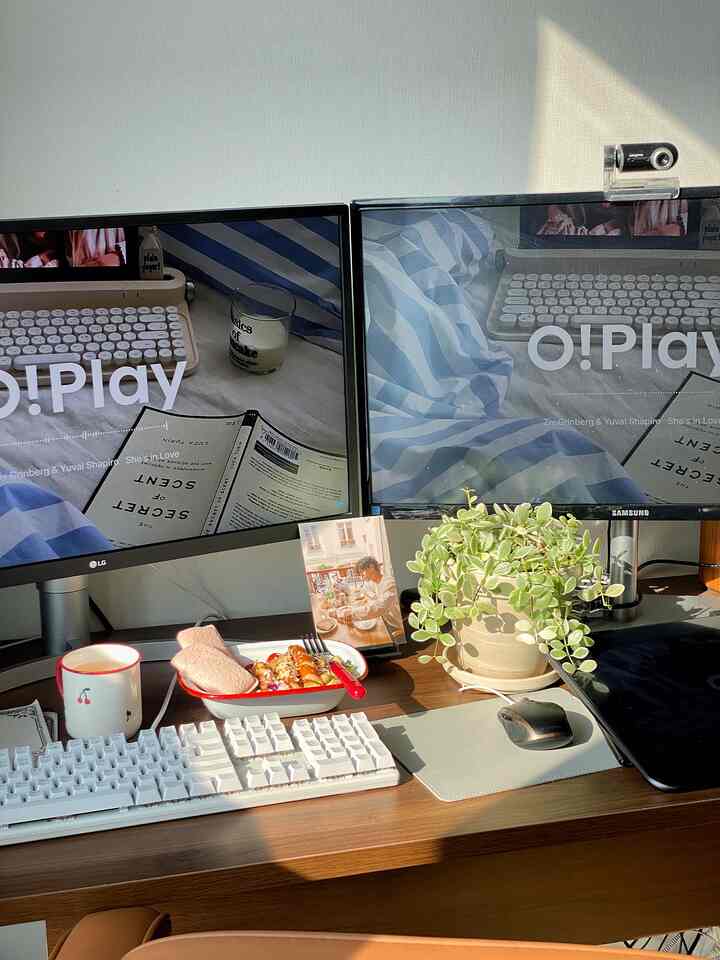 白と茶色のトーンのホームオフィス、デュアルモニターと植物が配置された落ち着いた在宅勤務の空間