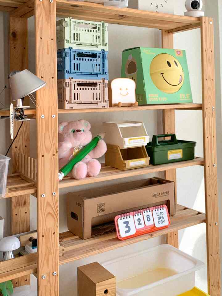 Natural wood tone shelf filled with colorful storage boxes and cute character items creating cozy space