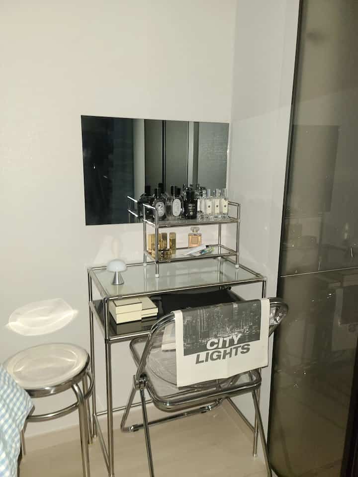 白い背景のミッドセンチュリーモダンスタイルの寝室隣のモジュール化粧台、スチールスツールとアクリル折り畳み椅子が配置された洗練されたモダンな化粧台空間