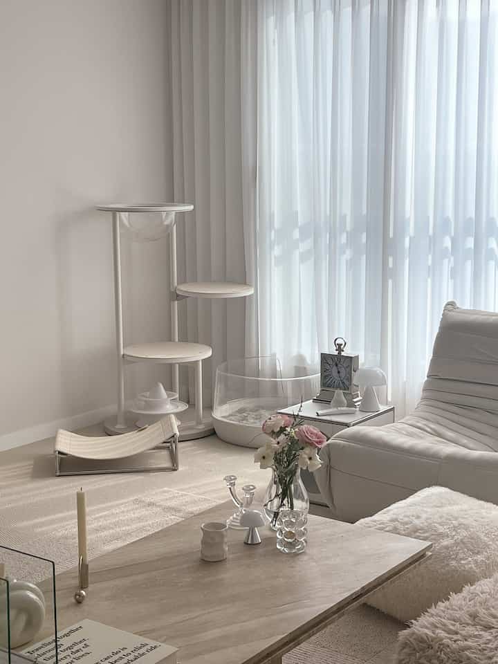 Bright white-toned living room featuring a cat tower and transparent cat litter box, creating a pet-friendly natural modern interior space