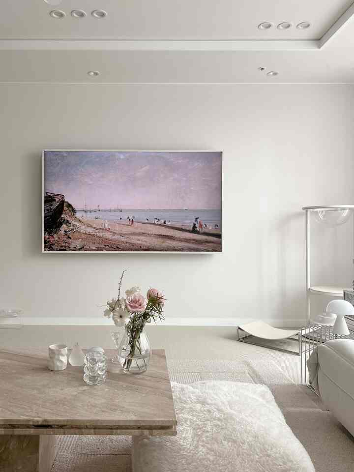 Bright white-toned living room featuring natural stone coffee table centered and large landscape wall art with a simple modern atmosphere