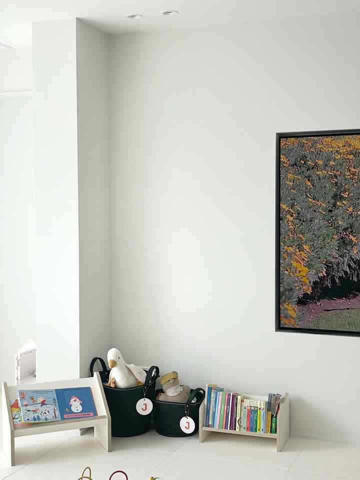 ホワイトとナチュラルトーンのリビング、子供用本棚とおもちゃ収納が配置された清潔感のある子供スペース