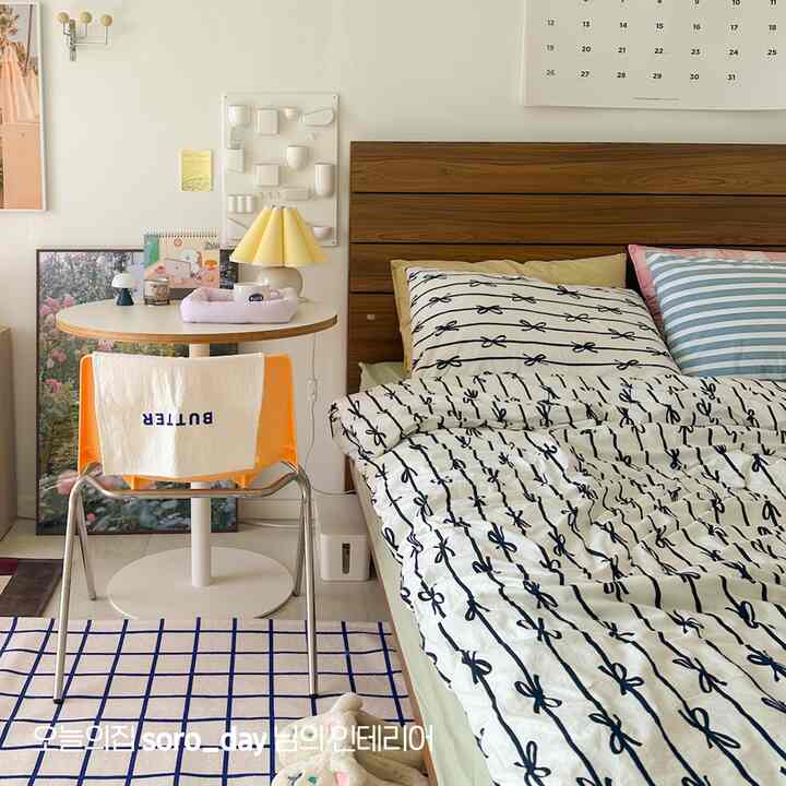 ナチュラルトーンとホワイトの調和が美しい一人暮らしの寝室。ミッドセンチュリーモダンのベッドと小さな丸テーブルが落ち着いた雰囲気を演出している。