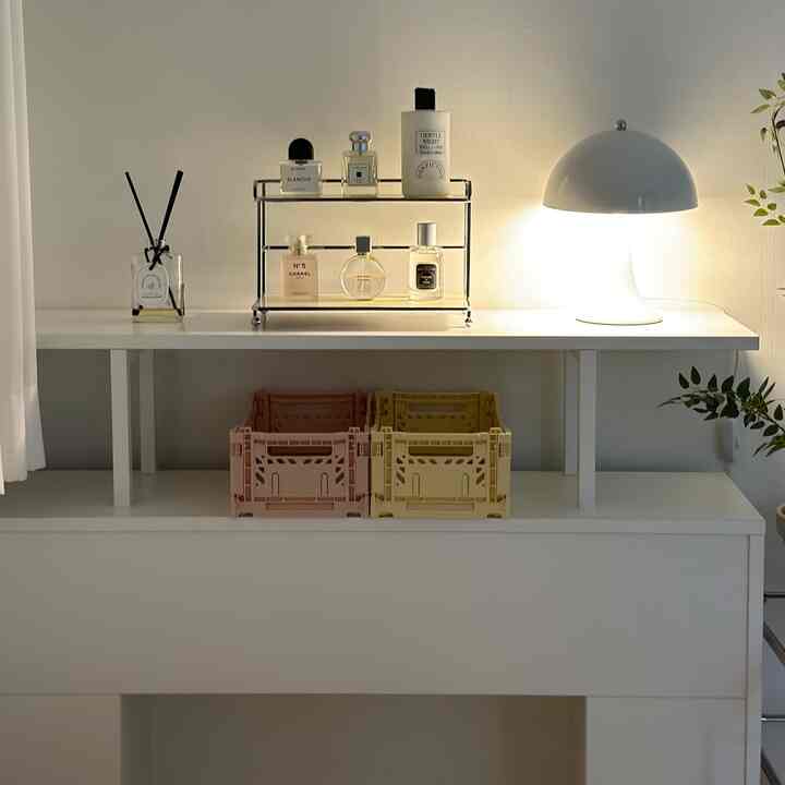 ホワイトの明るい寝室、ミニマルなチェストの上にディフューザーと照明が整然と配置された雰囲気のあるインテリア