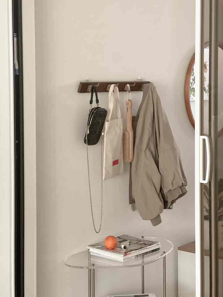 Natural tone entrance featuring a wooden coat rack and a clear side table in a simple, organized space