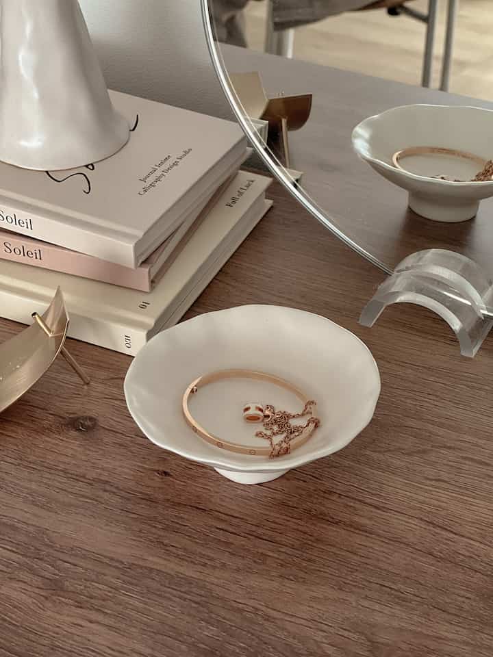 White-toned small plates placed on a wood-tone table surface, featuring simple interior decor with accessories