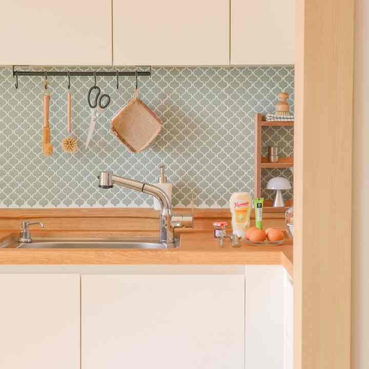 木目調と白のキッチン、タイルシートの壁と調理器具が配置された雰囲気のあるヴィンテージ空間