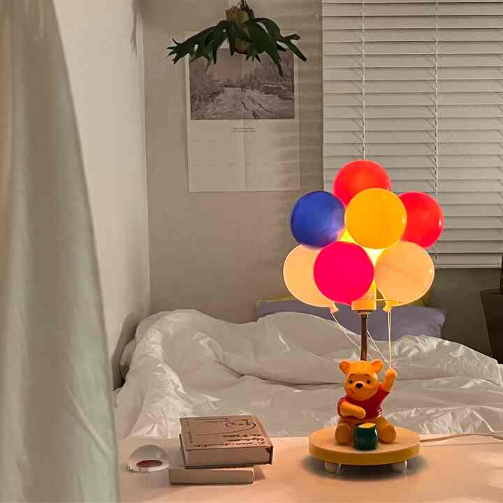 Cozy white bedroom featuring a vintage Winnie the Pooh balloon table lamp on a desk