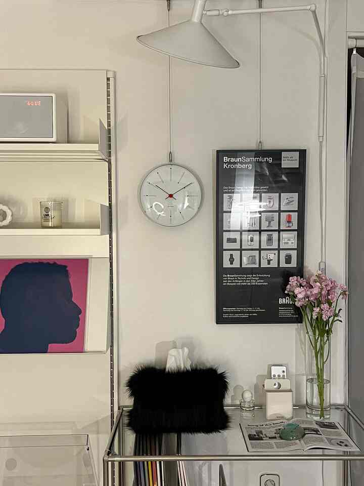 Ivory-toned simple dining room featuring modular shelves, poster, clock, and vase in a natural music listening space