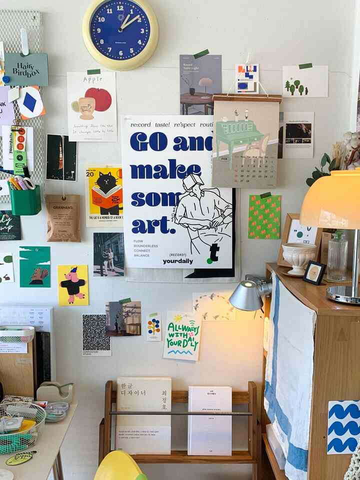 白とベージュのトーンのオフィス空間、感覚的なポスターや額縁が壁に飾られ、テーブルランプが設置された雰囲気のあるインテリア