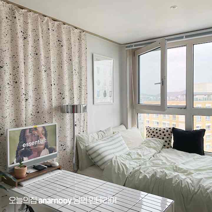 白とグレーのトーンの寝室、明るい窓とパターンカーテン、ベッドとデスクが配置されたシンプルモダンな空間