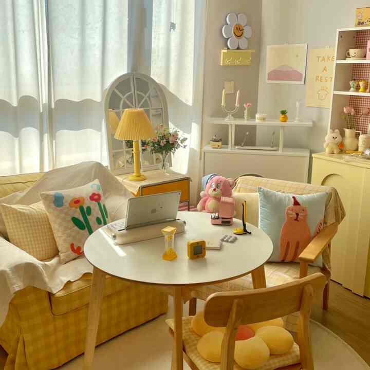 Yellow and natural toned studio apartment with a yellow sofa, round table, dog-themed cushions and plush toys in a cozy interior