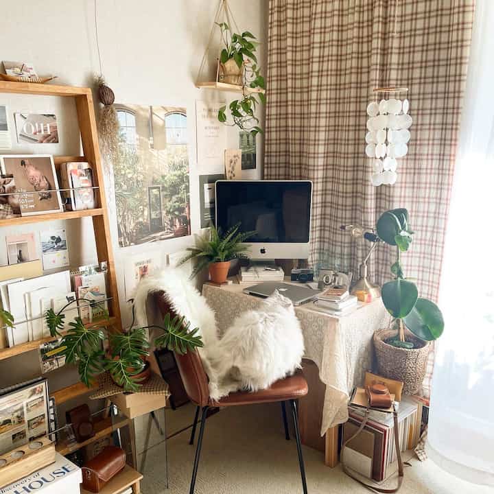 Wood tone and beige curtain home office featuring a white cat and multiple plants with cozy atmosphere