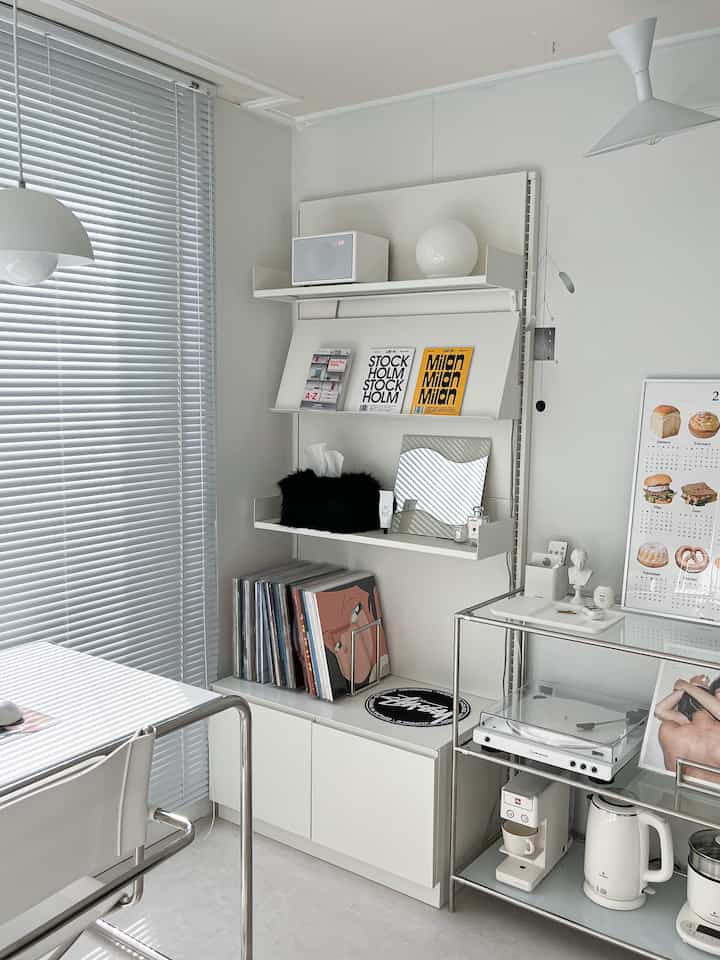 Bright white-toned music listening space featuring white desk, shelves, turntable, and speaker in a clean minimal ambiance