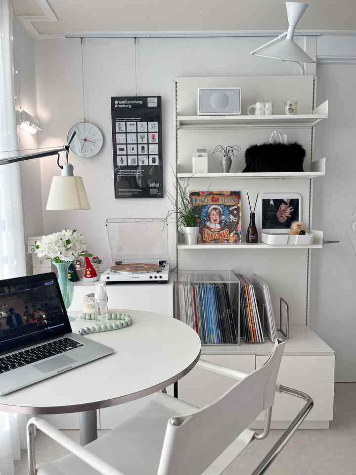 白を基調としたモダンなホームオフィス空間、丸いテーブルとLPコレクションの本棚が配置されたすっきりしたインテリア