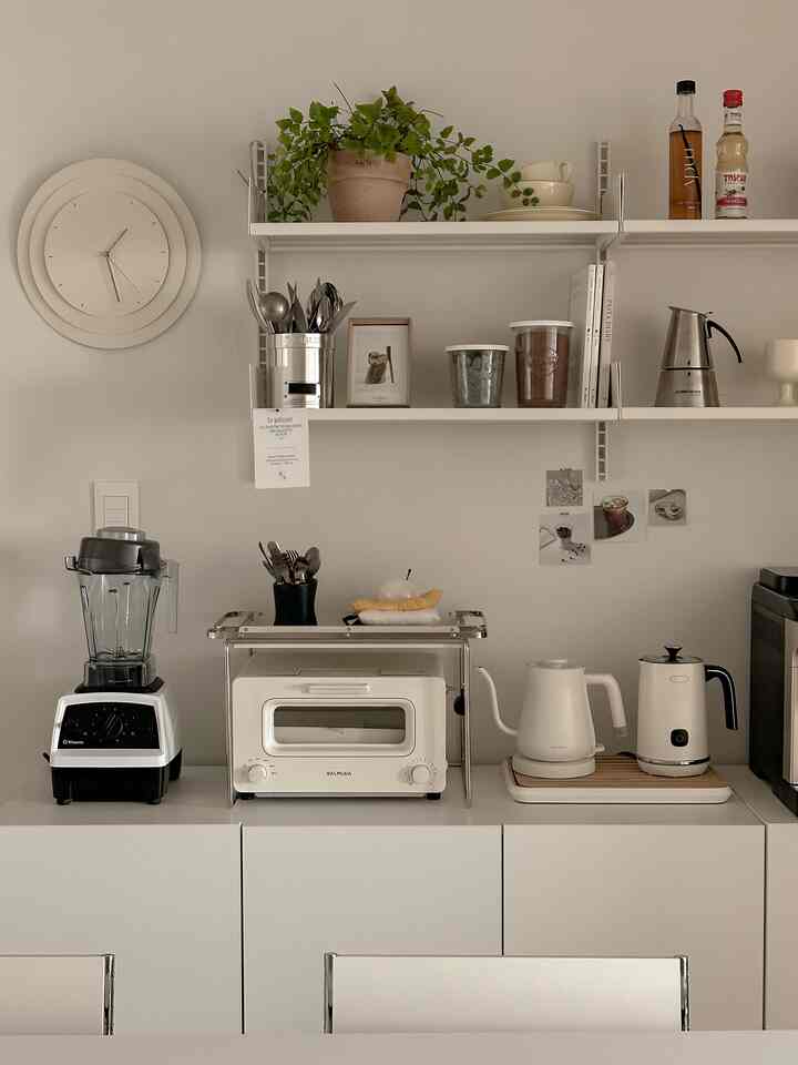 白を基調としたキッチン、すっきりとした棚と整頓された調理器具が配置されたミニマルなインテリア