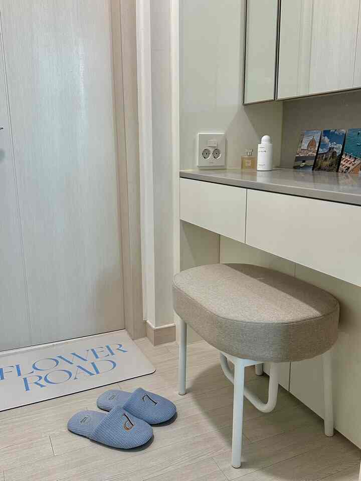 白とライトブラウンの色調の主寝室パウダールーム、シンプルなスツールと室内履きが配置された清潔感のあるインテリア