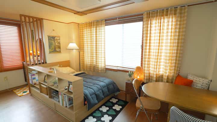 A 7-pyeong studio bedroom featuring yellow check curtains and wood tone furniture