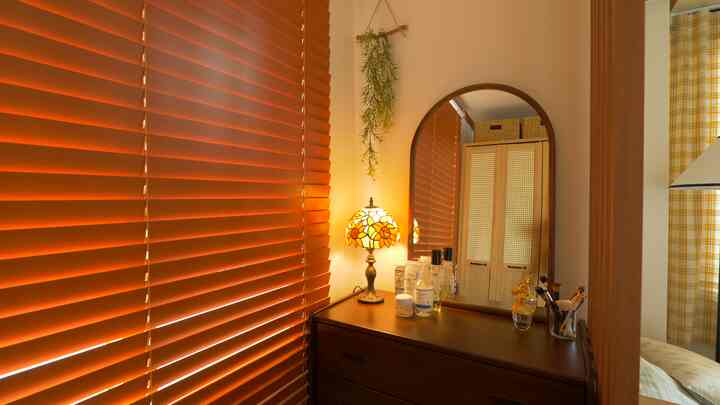 Warm brown wood tone powder room featuring an arch mirror vanity with stained glass lamp and yellow checkered curtain