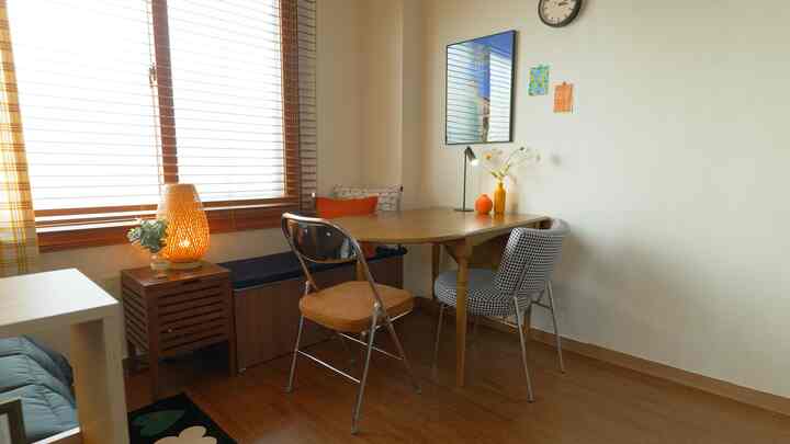 Wood tone and white small bedroom featuring an extendable table, storage bench, and varied chairs in a cozy space