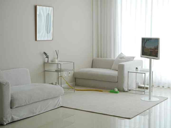 Bright white toned living room featuring modular fabric sofas separated into sections and transparent glass shelf tables, creating a clean space