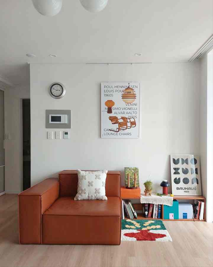 A small beige-toned living room featuring a red sofa, modern framed art, and cushions creating a cozy atmosphere.