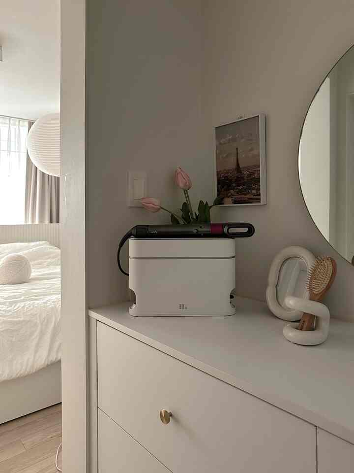 Natural tones and white bedroom vanity featuring neatly organized Dyson Airwrap and stand