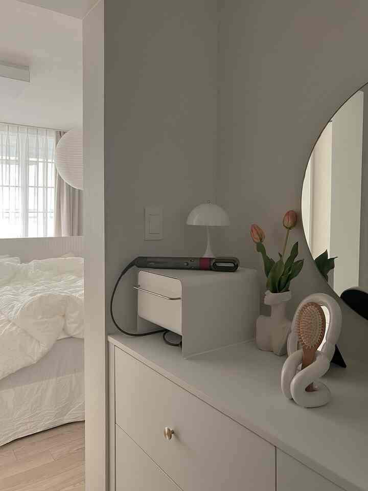 White-toned bedroom featuring a tidy vanity with storage, presenting a minimal and modern atmosphere