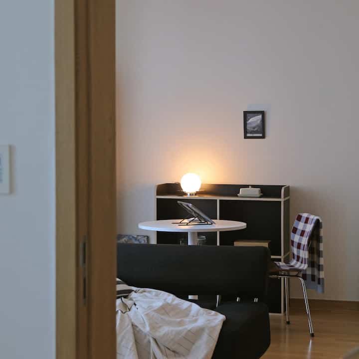 モノトーンのリビング、丸いダイニングテーブルとアームチェア、スローが配置された落ち着いた空間