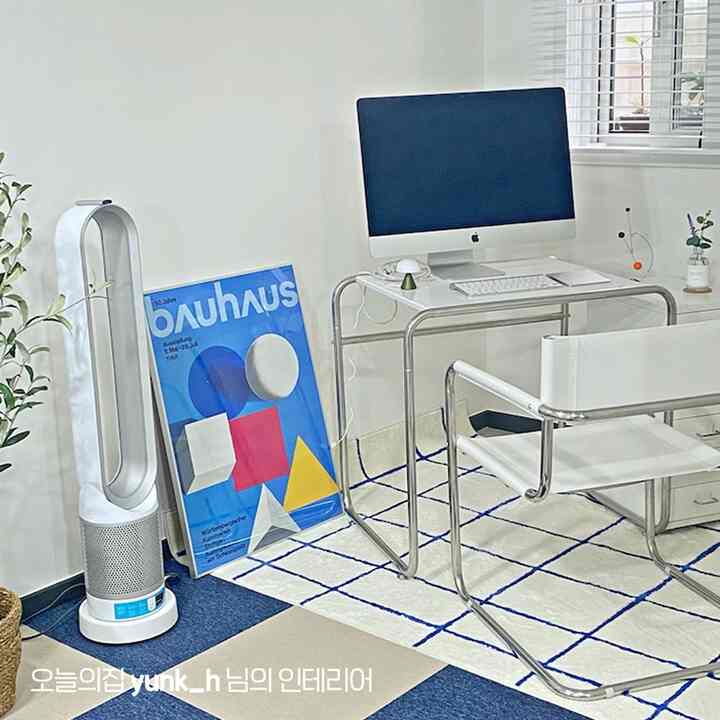 Compact home office in white and blue tones featuring a modern desk and chair with a Bauhaus poster in a neat setting