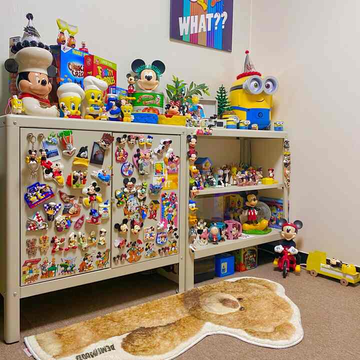Beige and gray toned kids' room with an IKEA cabinet covered in colorful Disney magnets and toys, creating a cozy and playful atmosphere