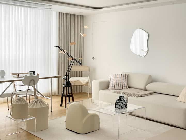 White and natural tone living room featuring a transparent acrylic table and simple furniture with modern and safe atmosphere