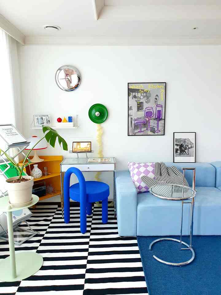 White and blue toned living room featuring a modular sofa, blue chair, side table, and modern clean layout