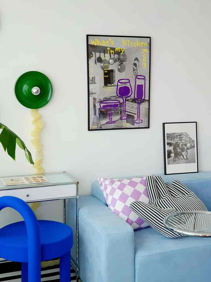 Minimal living room with light blue sofa, blue chair, white walls decorated with picture frames and unique green wall lamp