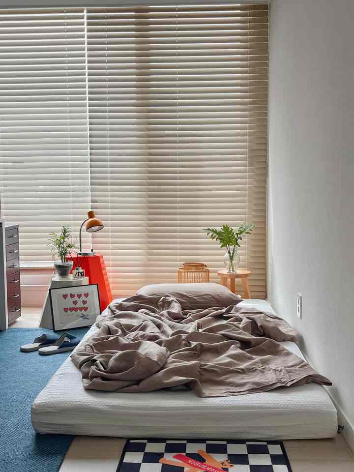 Beige-toned blinds and natural-colored bedroom featuring a central white mattress with brown bedding creating a cozy atmosphere