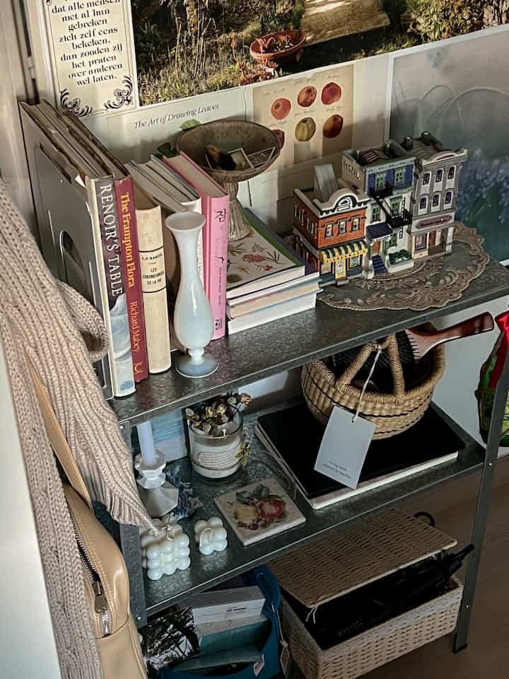 Cozy space featuring a natural beige tone 3-tier metal shelf arranged with books, candles, and decorative baskets