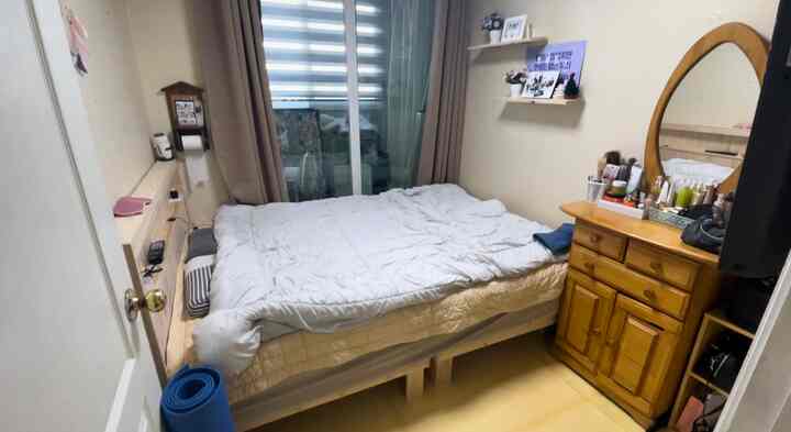 Cozy small bedroom featuring wood-tone furniture and beige curtains with central bed