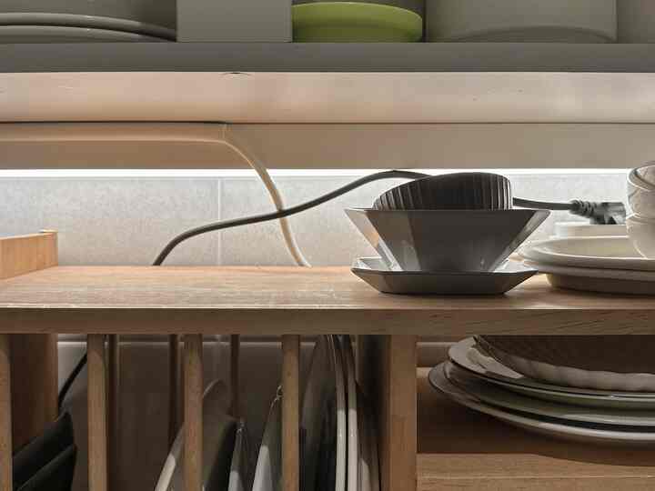 Natural wood tone dish rack in kitchen storage space featuring neatly organized plates and bowls