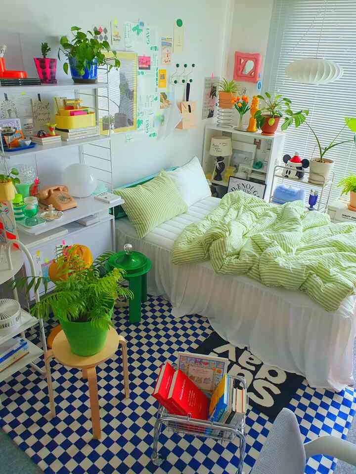 White and green toned bedroom featuring plants, bookshelf, and stool with a natural modern style atmosphere
