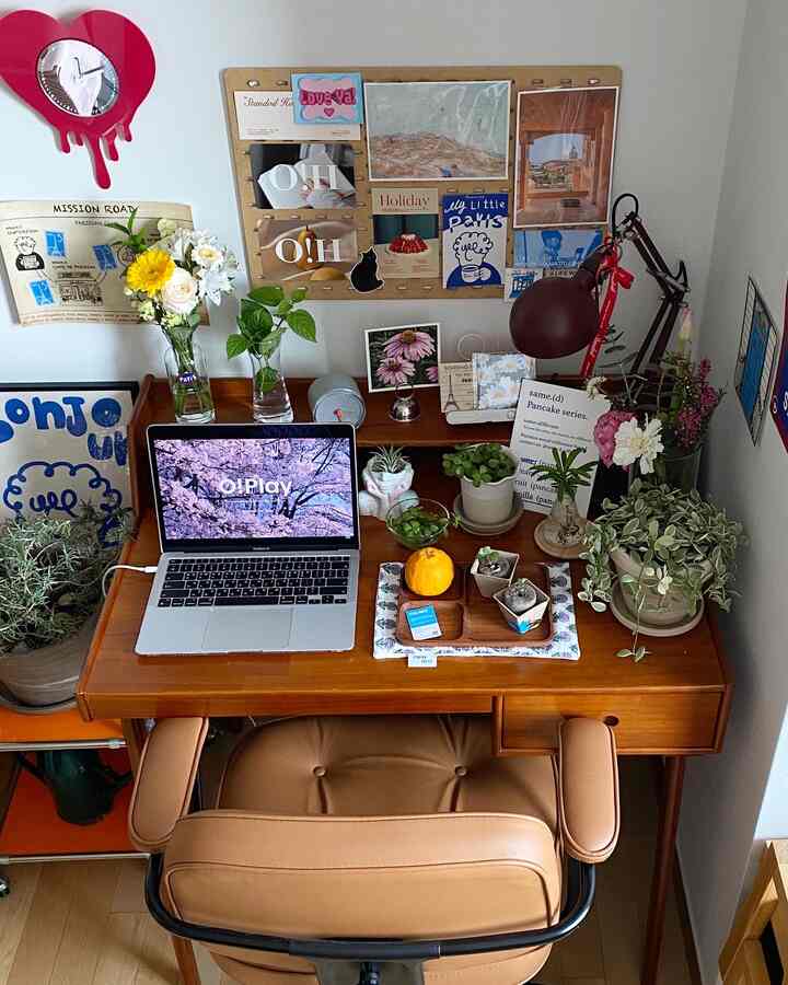 Natural wood-toned home office space featuring various plants and a laptop on a tidy desk with a comfortable office chair