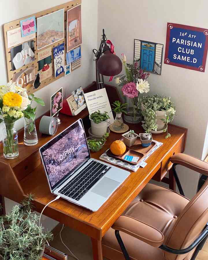 ブラウンの木目調と白い壁のナチュラルなホームオフィス、デスクに花瓶と植物が配置された落ち着いた雰囲気の空間