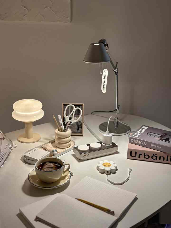 Cozy home office desk in white and beige tones featuring table lamps and reading accessories on a minimalist surface