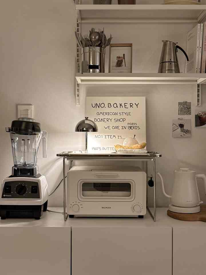 白とクロムの色調のキッチン、照明と調理家電が整然と配置されたモダンでミニマルなインテリア