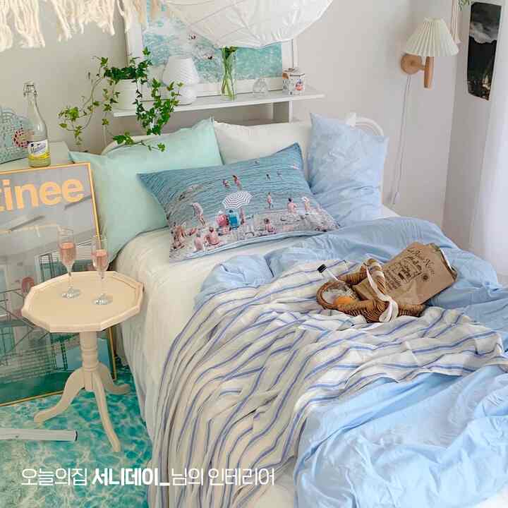 パステルブルーとホワイトの色調の寝室、枕と寝具が配置された自然な雰囲気のある空間