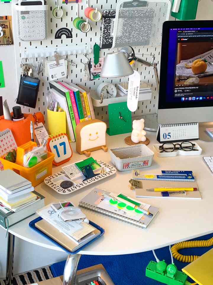 White and orange toned home office desk featuring stationery items, clock, and modern lamp creating a cozy stationery space